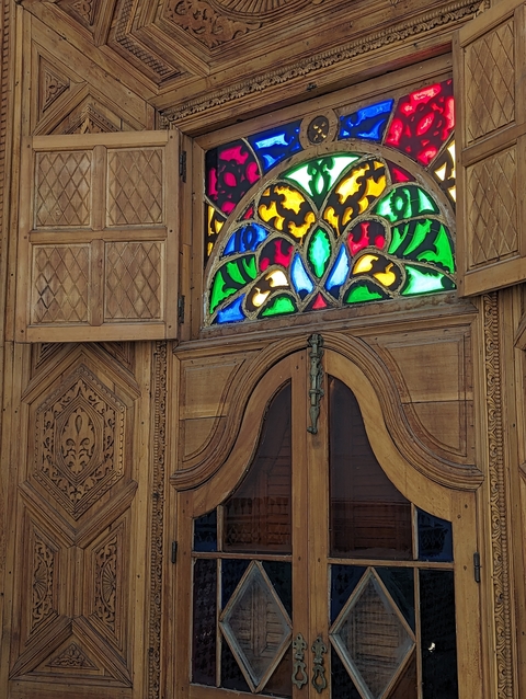       Colorful stained glass window and wooden door detail.
  