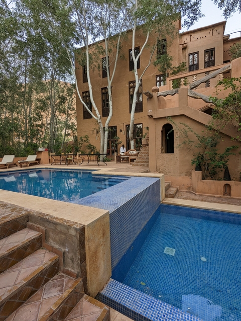       A poolside area with lounge chairs and a person sitting by a building.
  