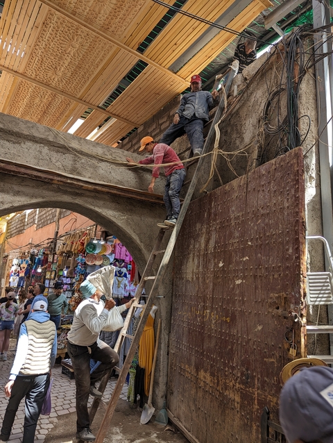       Construction work on an archway with people working and others passing by.
  