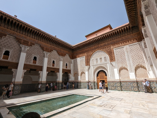       Intricate courtyard with tourists exploring.
  