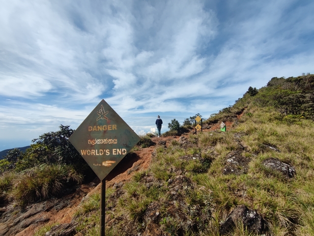       Person standing near a sign that says 'Danger World's End'.
  