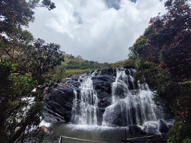       A wide waterfall cascading down a rocky cliff.
  
