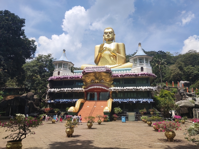       Golden Buddha statue in front of a temple entrance.
  
