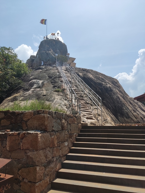       Staircase built on a rocky hill under a clear sky.
  
