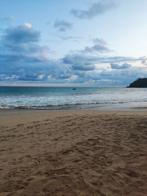       Waves crashing on a beach with clouds overhead.
  