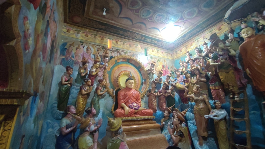      Statue of Buddha surrounded by colorful carvings.
  