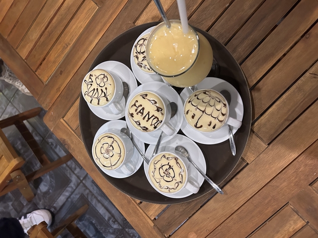Cups of decorated coffee on a tray with juice.