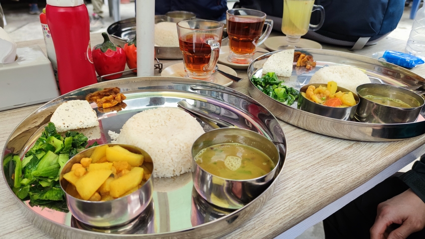 Traditional meal with rice, vegetables, and curry on a dining table.