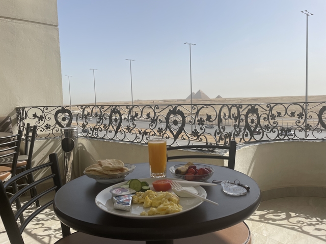 Breakfast tray on a balcony overlooking the pyramids in the distance.