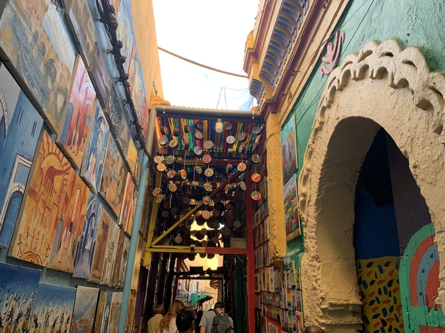       Colorful alley with paintings and hanging decor.
  