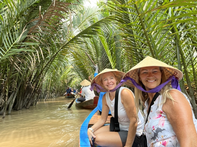 Tourists paddling through a waterway lined with palm trees.