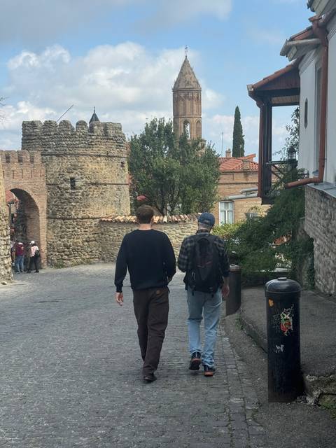       Two people walking near an ancient building.
  