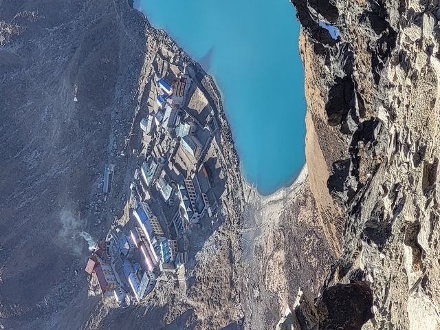 Aerial view of a mountain village by a turquoise lake.