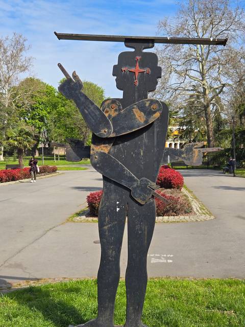       Sculpture of a human figure made of metal in a park.
  