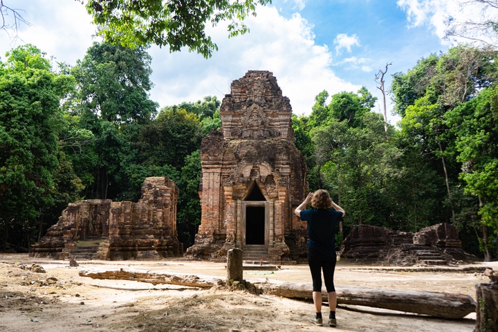 Person photographing an ancient stone temple.