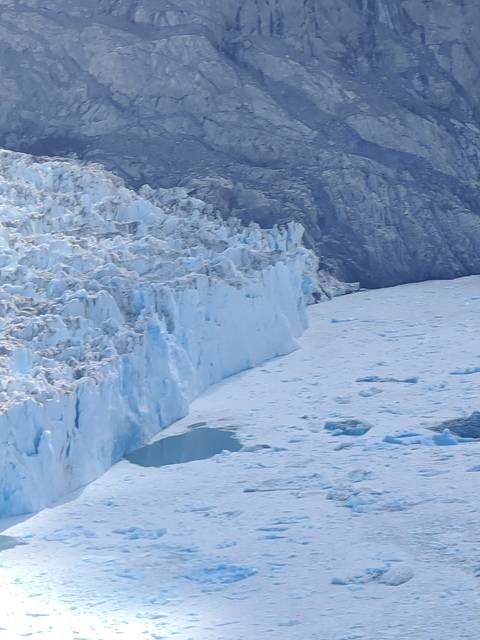       Close-up of a glacier against rocky terrain.
  