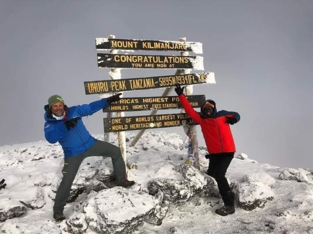       Two climbers at Uhuru Peak with snow around.
  