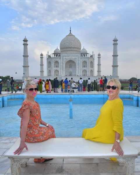       Two women posing with the Taj Mahal in the background.
  
