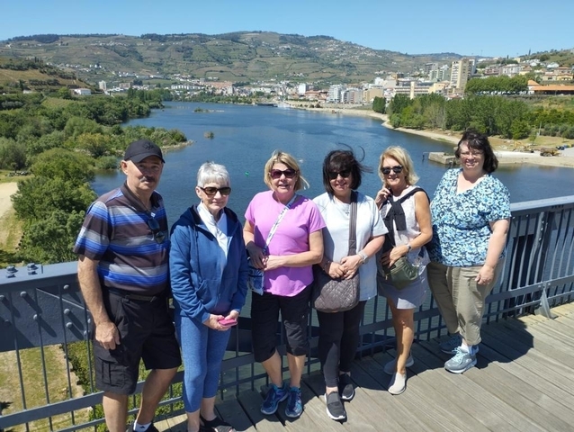 Group of people posing on a railing with a scenic river view.