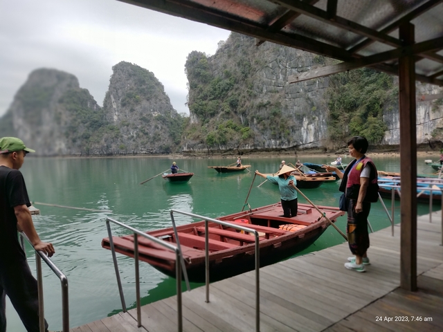       People rowing boats in a picturesque bay with rocky cliffs.
  