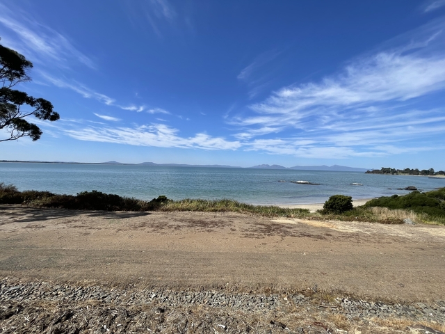       Sandy beach with a distant view of mountains.
  