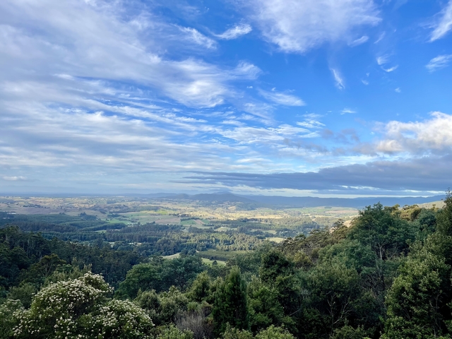       Panoramic view of a valley with rolling hills and blue sky.
  