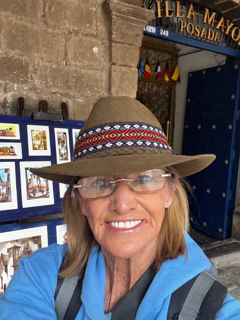      Woman in traditional attire smiling near a stone wall with signs.
  