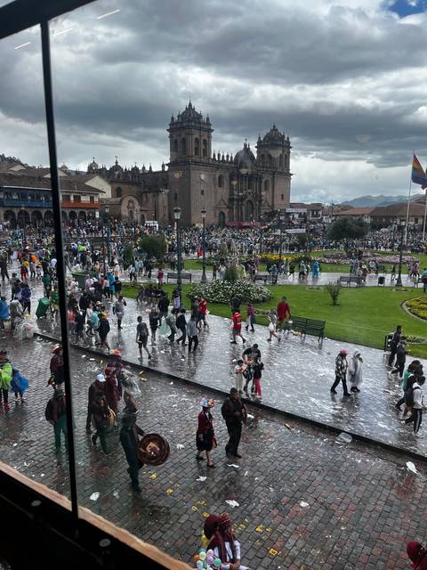       Crowds and performers in a busy city square near historical buildings.
  