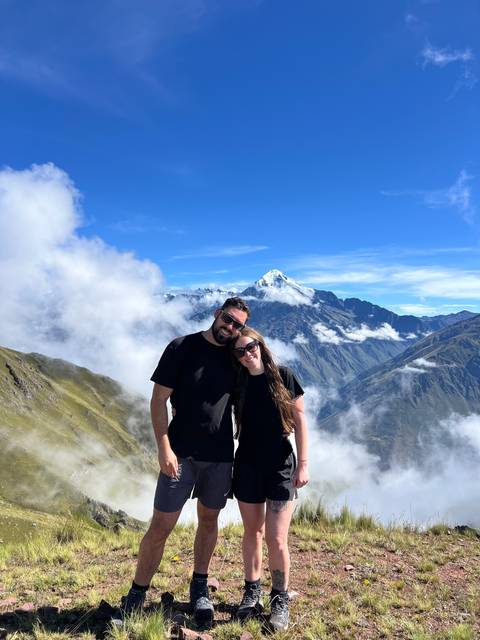 Couple standing on a mountain trail with a view of a peak.