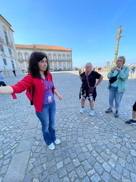 Two women standing on a cobblestone square with historical buildings.