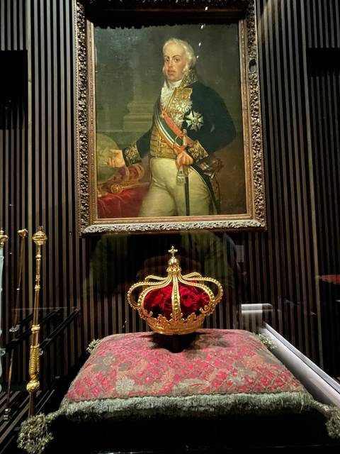       Framed painting and a crown on display.
  