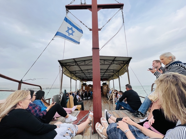 People sitting on a boat with an Israeli flag.