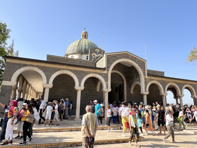       Crowd at a religious site with a domed building.
  