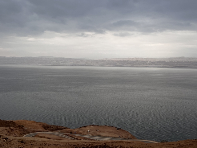       A large calm body of water with hills on the horizon.
  