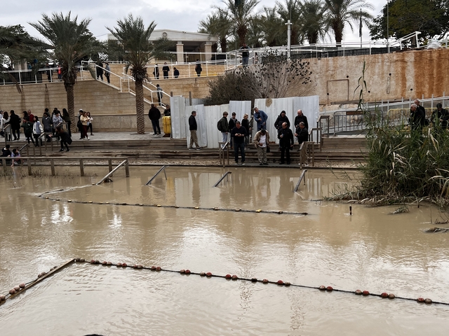       Riverside scene with tourists on a wooden deck.
  
