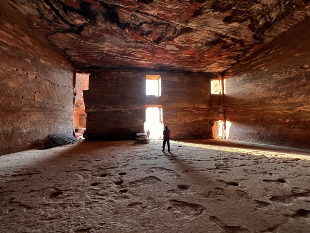       Person standing inside a large ancient cave-like structure.
  