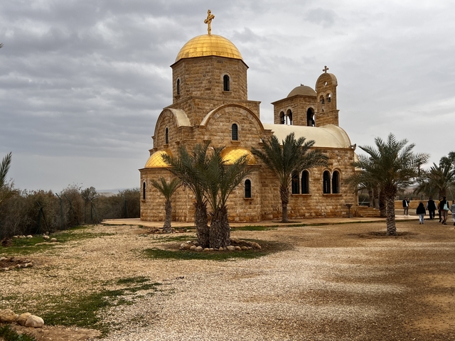      Beautiful church with golden domes, surrounded by palm trees.
  