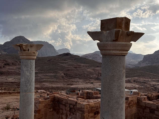       Two ancient columns with barren hills in the background.
  