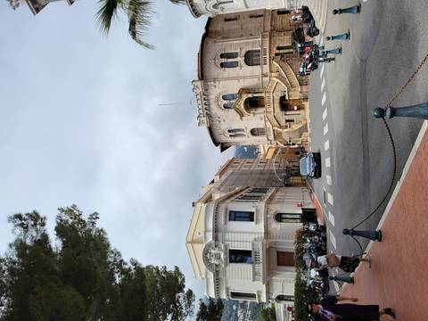      Scenic street view with ornate buildings and people walking.
  