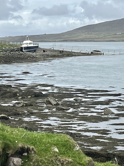 Coastal area with rocky shore and distant hills.