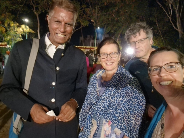       People posing happily together outdoors at night.
  
