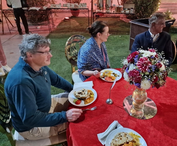       Group of people dining outdoors with festive decor.
  