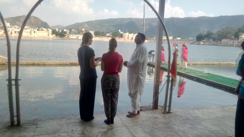       People standing by a lake with hills in the background.
  