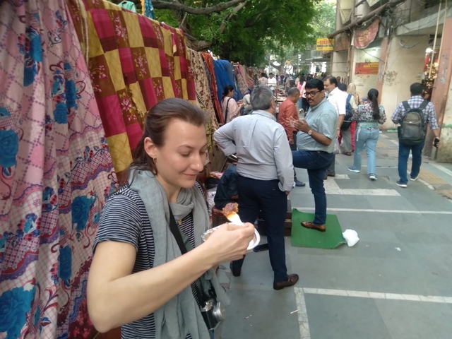       Woman enjoying street food in a bustling market.
  