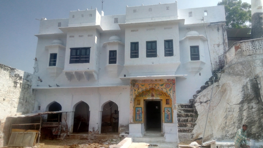      A white building with decorative artwork and arched windows.
  