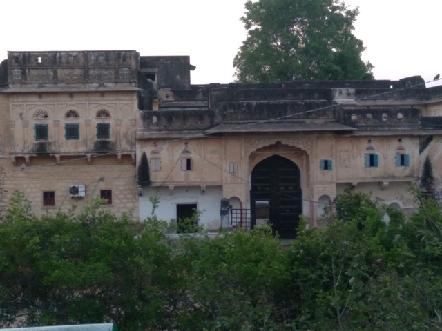       A historical building with green foliage in the foreground.
  