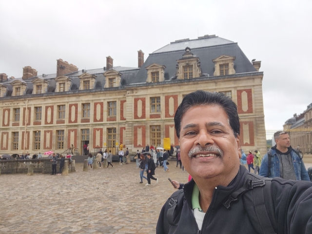 A smiling man with a historic building in the background.