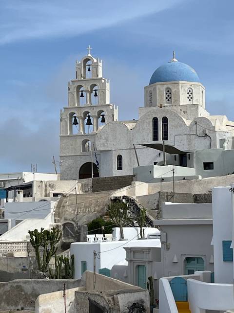 Side view of a church with blue domes and bells, partially obscured.