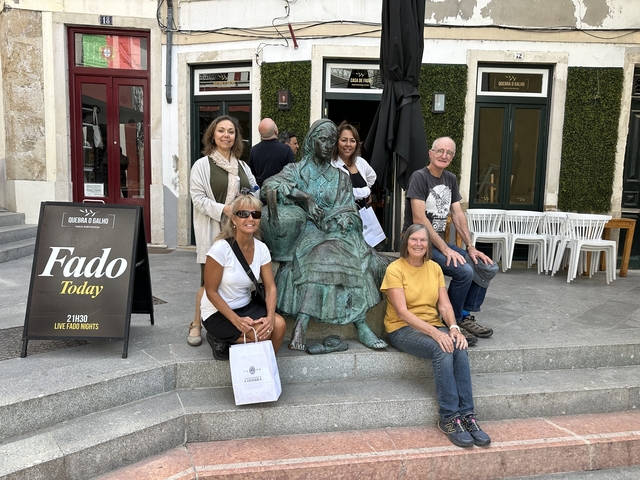 Group of tourists posing with a bronze statue outside a building.