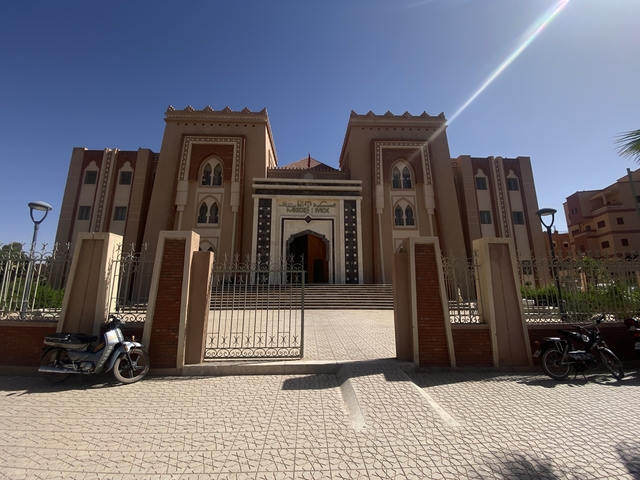       Modern building with decorative gate and motorbikes parked outside.
  